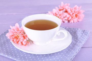 Pink chrysanthemums and cup of tea on wooden table