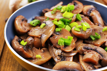Delicious fried mushrooms in pan on table close-up