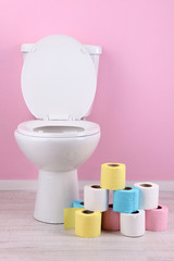 White toilet bowl and colorful rolls of toilet paper, in