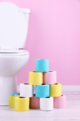 White toilet bowl and colorful rolls of toilet paper, in
