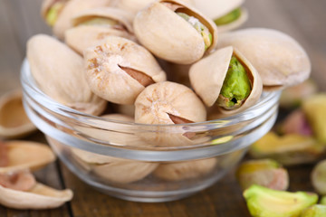 Pistachio nuts in glass bowl on table close up