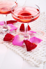 Composition with pink sparkle wine in glasses and rose petals