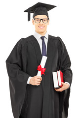 Male student in graduation gown posing with a diploma