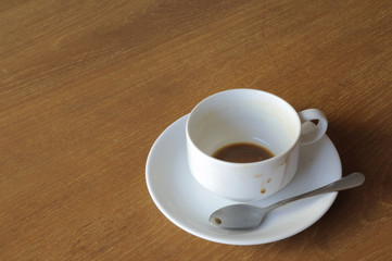 White coffee-cup with spoon on wooden table