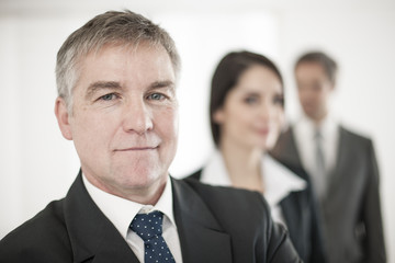 senior businessman at foreground and his team behind him