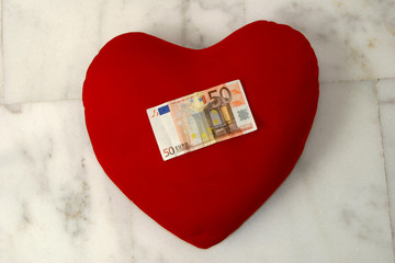 Money (fifty Euros) on heart denoting concepts of love and money