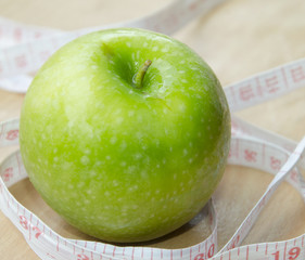 Green apple core and measuring tape. Diet concept