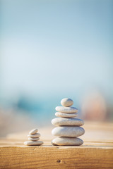 zen stones jy wooden banch on the beach near sea. Outdoor - obrazy, fototapety, plakaty