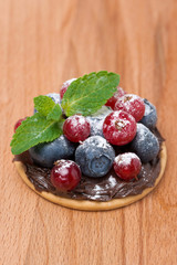 cake with chocolate cream and berries on wooden background