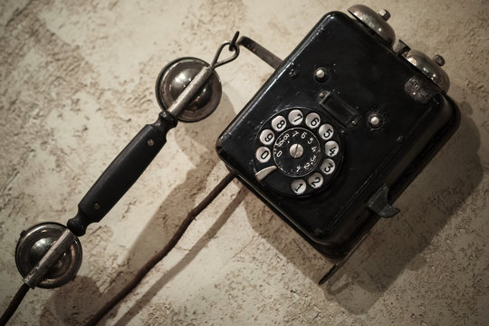 Vintage Black Phone Hanging On Old Gray Concrete Wall