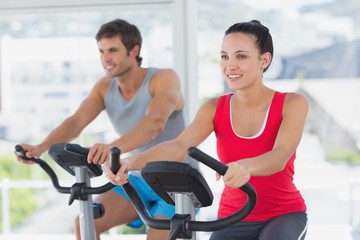 Fototapeta premium Smiling young couple working out at spinning class