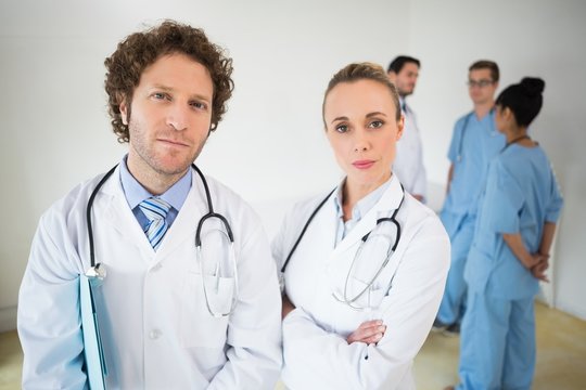 Confident doctors with colleagues in background