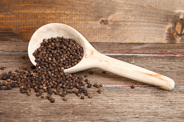 black peppercorns in wooden spoon