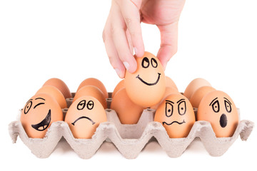 Funny faces painted on brown eggs in a tray