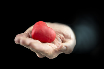 Man cupping a red heart in his hand