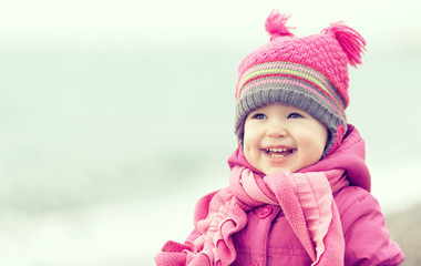 Happy baby girl in a pink hat and scarf