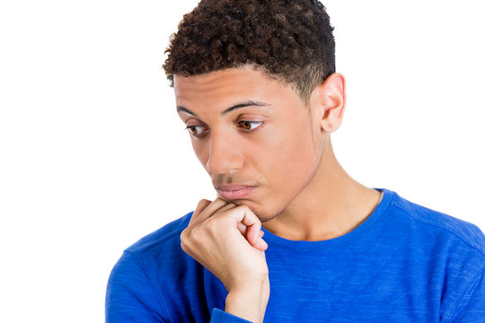 Young man thinking daydreaming, looking downward, chin on fist