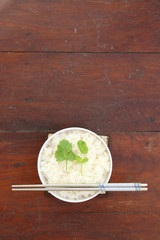 Steam rice in white bowl with chopstick, wood background