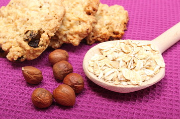 Oatmeal cookies with flakes and hazelnut on purple background