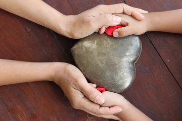woman and boy hands holding red and metal heart shaped.
