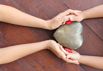 woman and boy hands holding red and metal heart shaped
