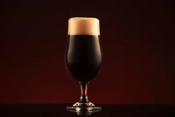Zelfklevend Fotobehang Glass of dark beer on brown background © ValentinValkov