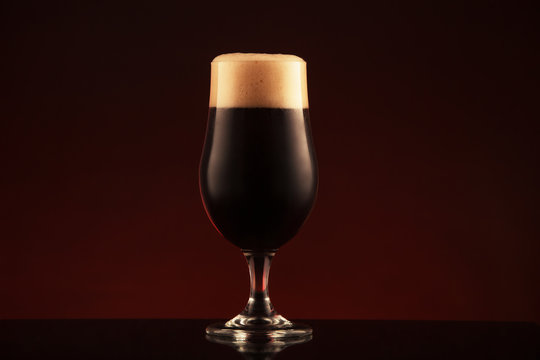 Glass of dark beer on brown background