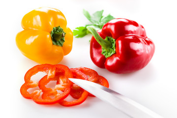 Colored peppers with slice over white background