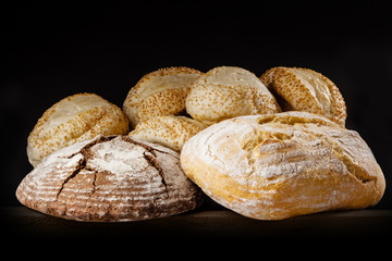 Fresh bread and buns with sesame on dark background.