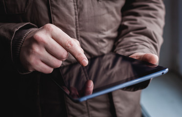 The man uses a tablet PC. Modern gadget in hand.