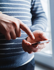 The man is using a smartphone. Modern mobile phone in hand.