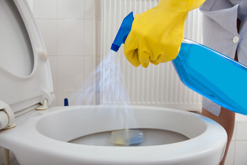 Person's Hand Spraying In Bathroom