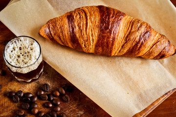 Espresso in a glass cup with a croissant