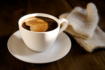 Sunlit black coffee and mittens in winter