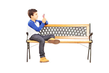 Boy seated on bench and playing cards with imaginary friend
