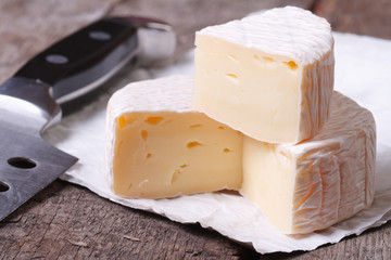 brie cheese on old wooden table and knife closeup