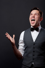 Handsome young man staying against gray wall