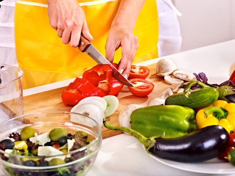 Female hand cutting vegetable at kitchen.