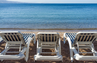 Three deckchairs overlooking calm seaside