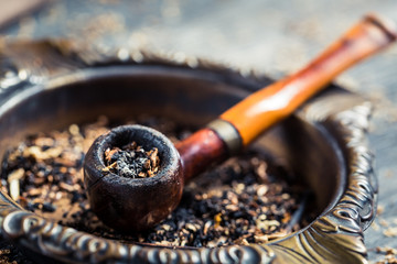 Closeup of old wooden pipe in an ashtray