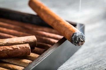 Afwasbaar fotobehang Brandende sigaar met rook op houten humidor © shaiith