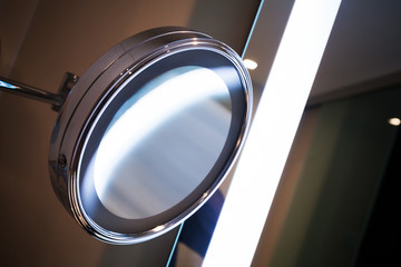 Round mirror with bright illumination in the bathroom