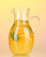 Orange lemonade in pitcher on yellow background