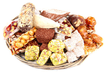 Tasty oriental sweets on wicker tray, isolated on white