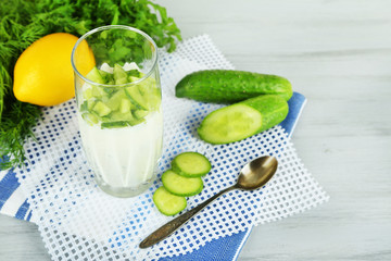 Cucumber yogurt in glass, on color napkin, on wooden