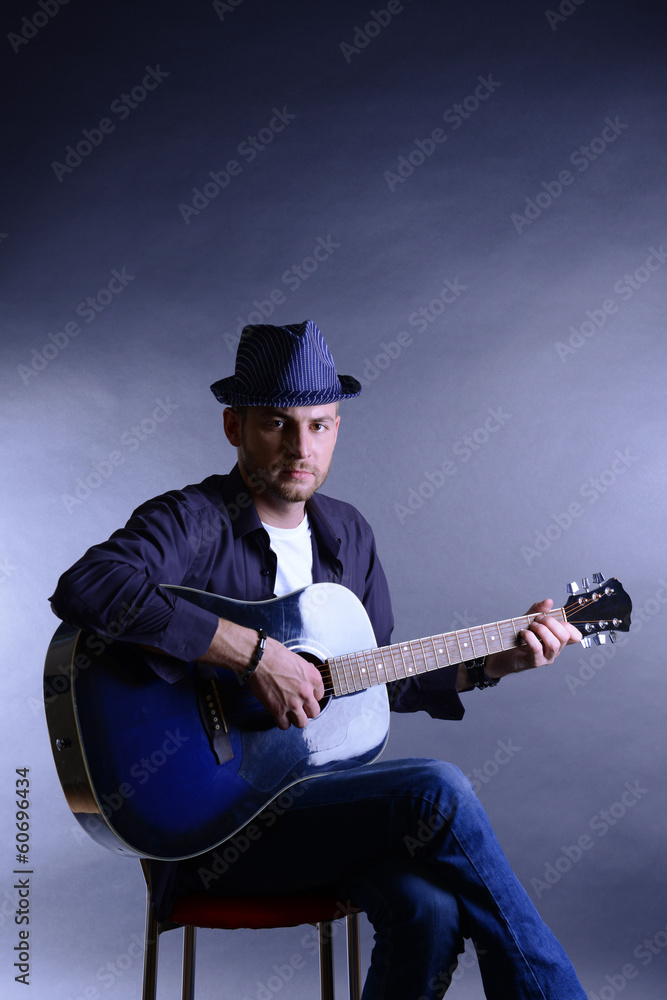 Wall mural Young musician playing acoustic guitar and singing,