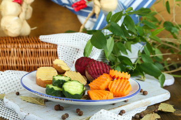 Beautiful sliced vegetables, on plate, on wooden background