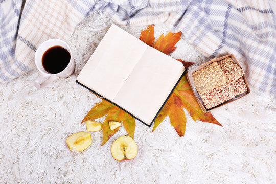 Composition with warm plaid, book, cup of hot drink,