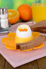 Boiled egg in egg cup on table on bright background