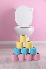 White toilet bowl and colorful rolls of toilet paper, in